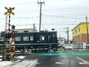 万代町の踏切を通過するいさりび鉄道の写真