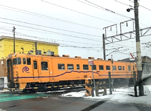 万代町の踏切を通過するいさりび鉄道の写真